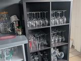 bottles and glasses are stacked on a shelf in a kitchen