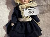 a doll that is holding a sign with a name on it
