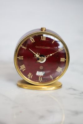 une horloge rouge à chiffres romains posée sur une table en marbre