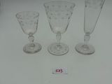 three glass goblets and a wine glass are sitting on a table