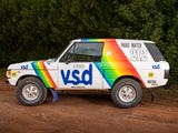 a multicolored vehicle parked on the side of a dirt road