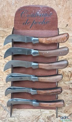five knives in a wooden holder with a sign on it