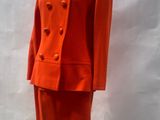 an orange suit on a mannequin stand in front of a white backdrop