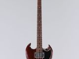 a close up of a red bass guitar hanging from a string