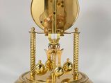 an image of a golden clock with a pendulum on a stand