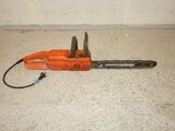 an orange chainsaw sitting on the floor next to a white wall