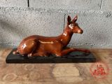 statue d'un cerf couché sur un socle en bois