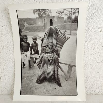 une photo en noir et blanc d'une femme assise sur un banc avec deux enfants