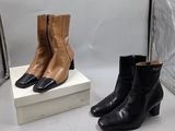 deux paires de bottes en cuir noir et marron posées sur une boîte blanche