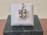 a small square pendant with a diamond on top of a marble block