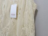 the top of a white sweater is hanging on a hanger