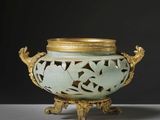 un vase vert avec un couvercle doré posé sur une table
