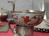 une nappe rouge sur laquelle sont disposés des assiettes et des cuillères en argent