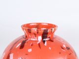 a red vase with a black and white design on it