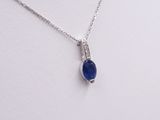 a close up of a necklace with a blue stone on a white surface