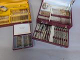 two sets of silverware in a case on a table