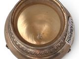 a small metal bowl with a lid on a white surface