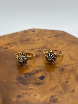 paire de bagues en or serties de diamants noirs, posées sur un support en bois