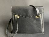 a black leather handbag with a gold clasp on the front