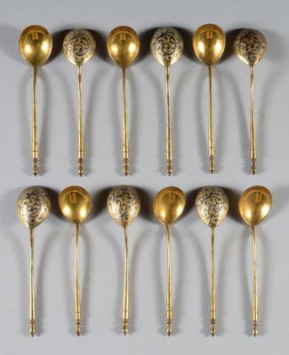 six gold spoons are lined up on a white surface