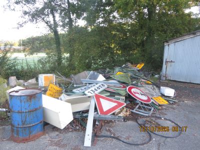 a pile of junk on the ground next to a blue barrel