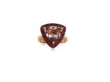 a close up of a ring on a white surface with a pink stone