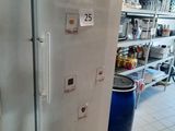 un réfrigérateur qui se trouve dans une cuisine, à côté d'une poubelle