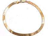 a close up of a gold necklace on a white surface