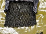 un sac à main noir entouré d'une chaîne, posé sur un fond jaune