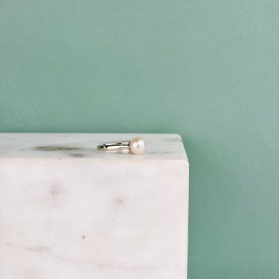 une bague en perle posée sur un bloc de marbre blanc