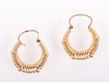 une paire de boucles d'oreilles en or sur fond blanc
