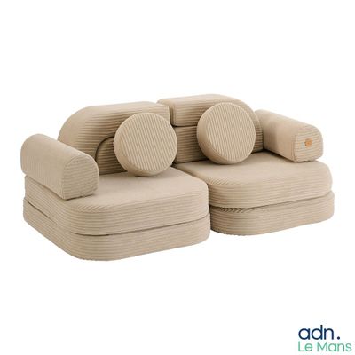 un canapé beige avec des coussins posés dessus