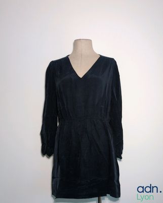 une robe en velours noir posée sur un mannequin contre un mur blanc
