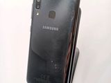 the back of a black samsung phone sitting on top of a white table