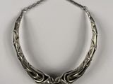 gros plan d'un collier en argent sur une surface blanche