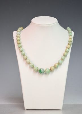 a close up of a necklace on a mannequin with green beads