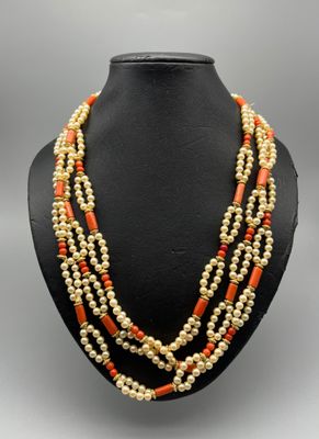 un collier de perles orange et blanches sur un mannequin noir