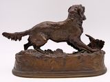 bronze statue of a dog on a rock with a bird in its mouth