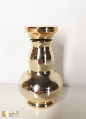 un vase doré posé sur une table blanche