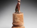 une petite statue représentant un chat assis sur un socle en bois