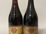 two bottles of red wine sitting next to each other on a table
