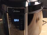 une cocotte-minute électrique noire et argentée posée sur une table en bois