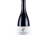 the bottle of red wine is sitting on a white surface