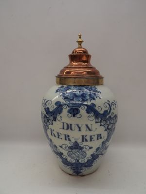 a blue and white vase with a gold lid on a table