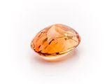 a close up of an orange sapphire stone on a white surface