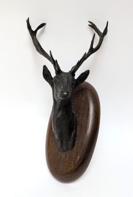 une tête de cerf fixée sur une plaque en bois accrochée au mur