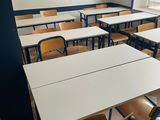 tables and chairs in an empty classroom with a window in the background
