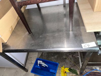 une table en métal sur laquelle se trouvent une poubelle bleue et une fleur jaune