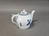 a white teapot with blue flowers on it on a table