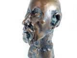 a bronze statue of a man ' s head on a white surface